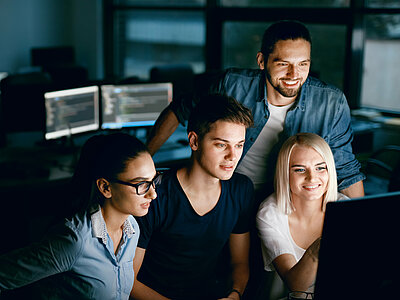 Group of young students sitting in front of a computer