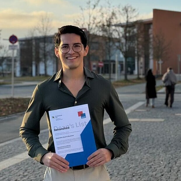 Alejandro standing in front of the university building