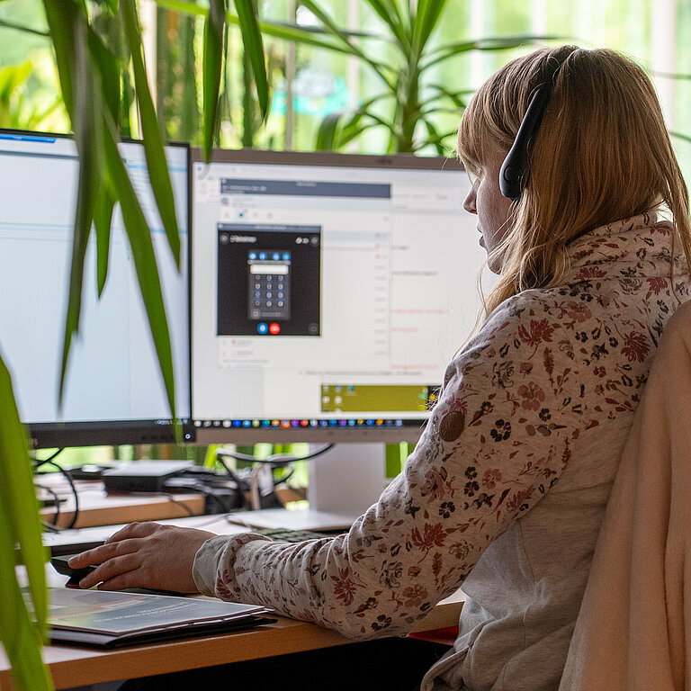 Frau mit Headset arbeitet am Computer