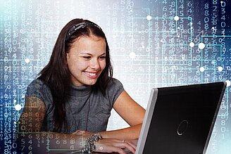 junge lächelnde Frau blickt auf den Laptop vor ihr
