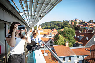 Studierende arbeiten mit Virtual Reality Brille auf Balkon