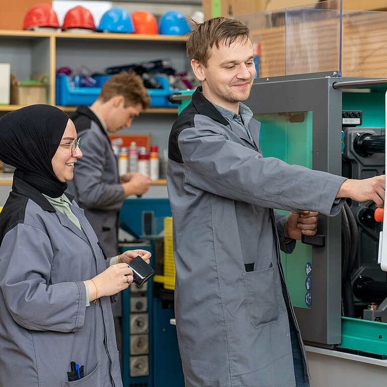 Mann zeigt Frau etwas an einer Maschine