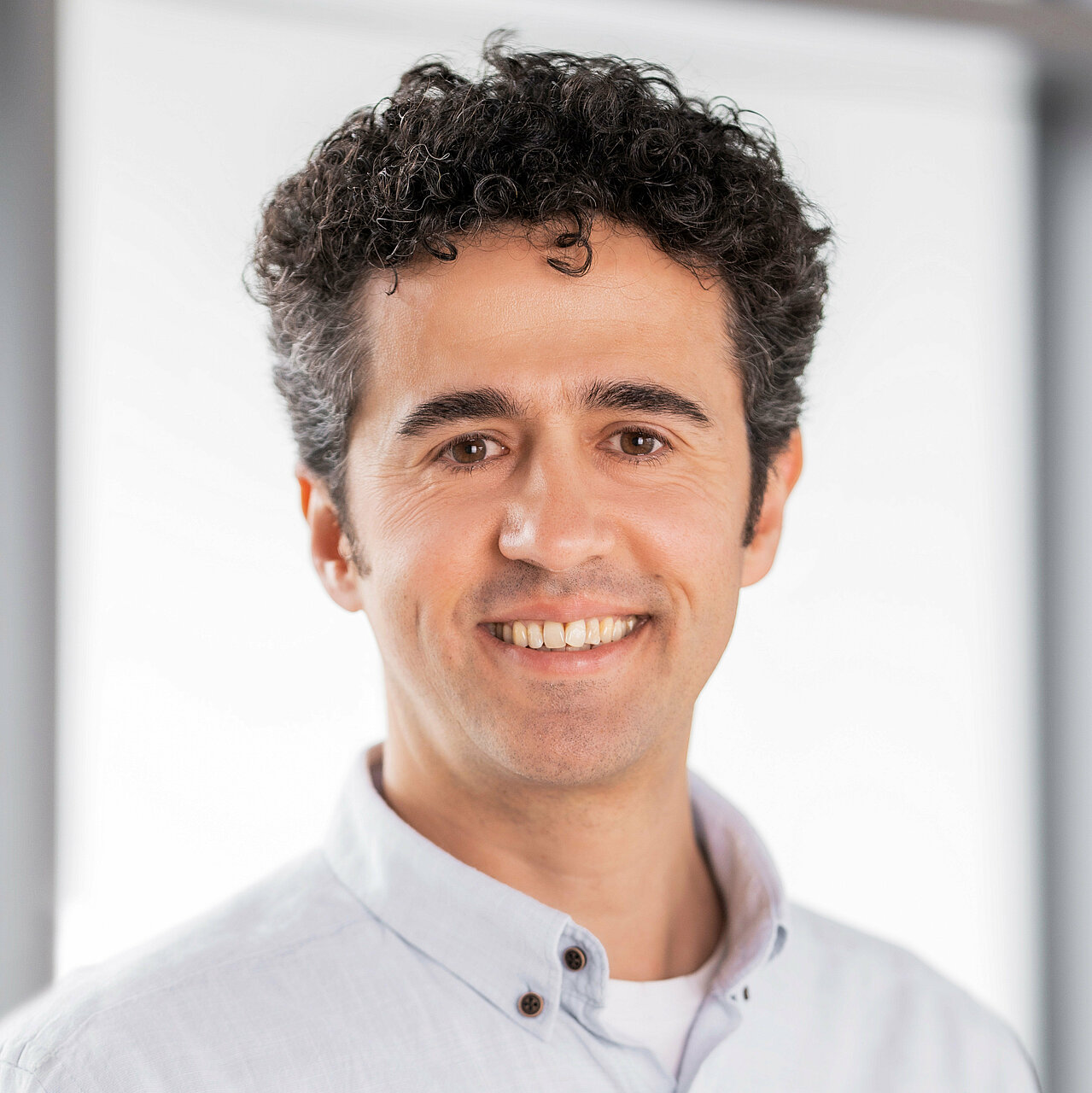 Portrait of Özgür smiling happily into the camera